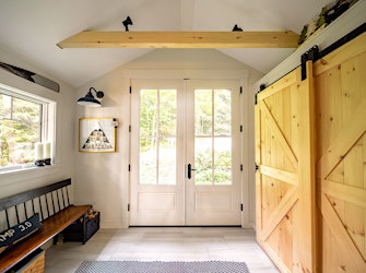 Mudroom with custom-built barn doors, designed to prevent the doors from swinging into the room (EP Lakehouse)