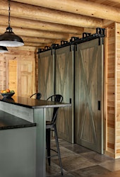 Custom-built barn doors on a triple track for a pantry. The stain is a custom finish, developed from the kitchen cabinet paint color. (Katahdin Log Home)